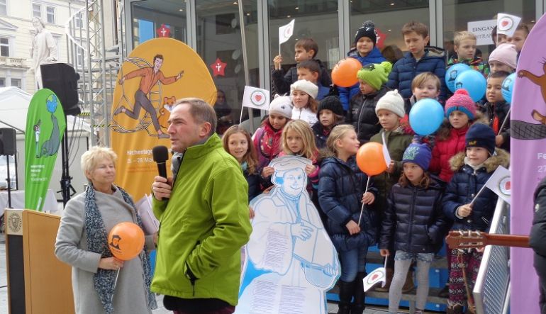 Superintendent Pfr. Mag. Manfred Sauer bei der Ansprache, im Hintergrund Volkschulkinder 